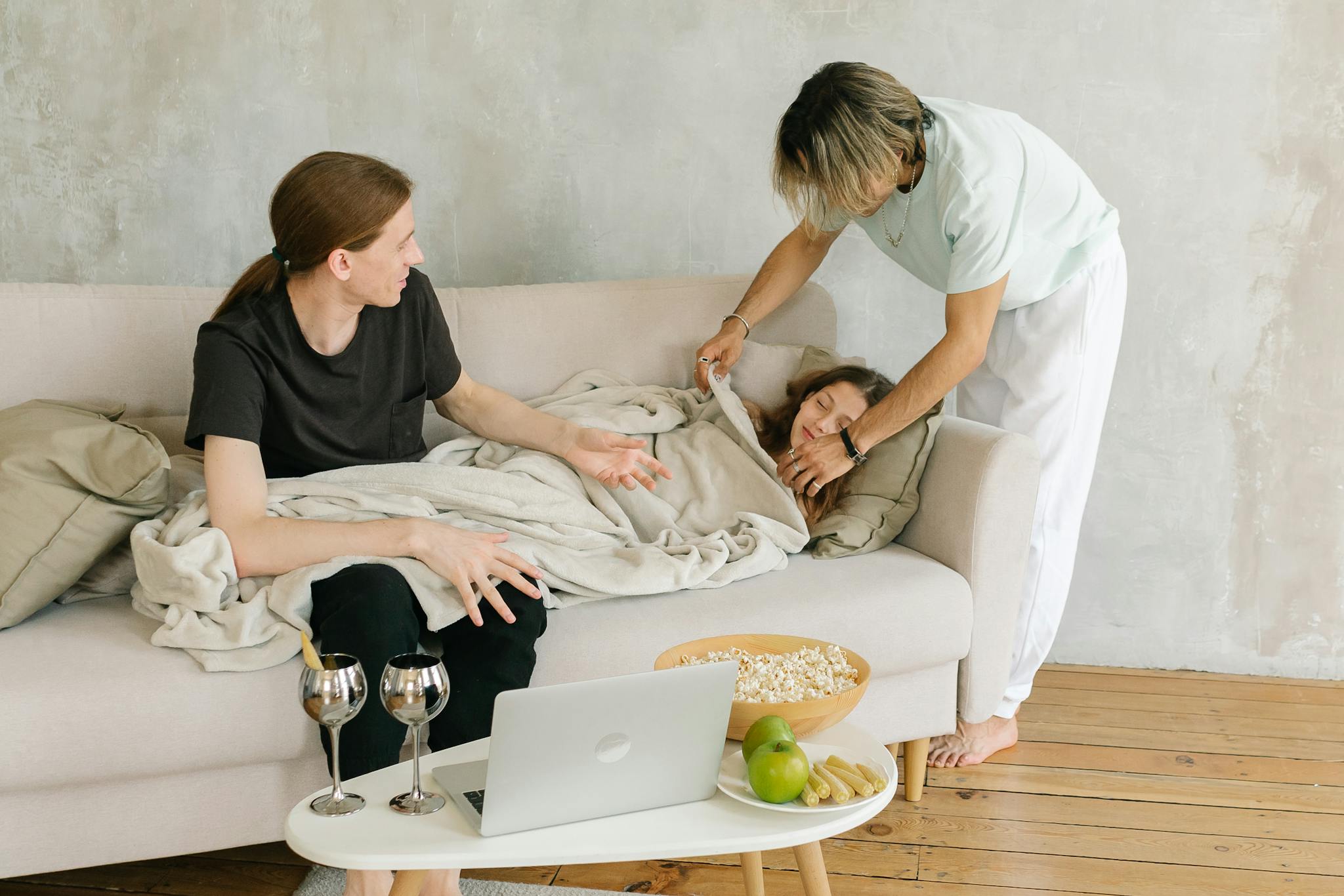 Family sitting on a sofa with a child wrapped in a blanket, creating a cozy living room scene.