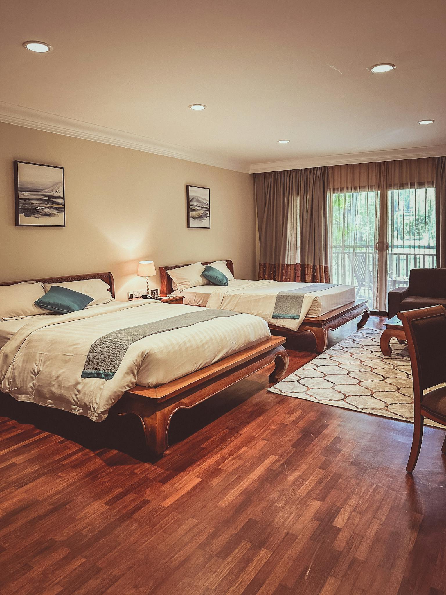 Spacious hotel room with two beds, wood flooring, and elegant decor. Ideal for leisure stays.