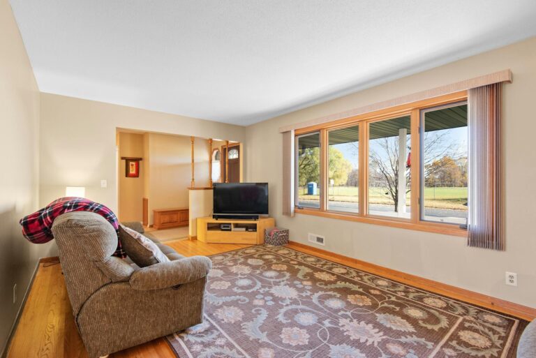 Spacious living room featuring a comfortable sofa, TV, and large windows with outdoor view.
