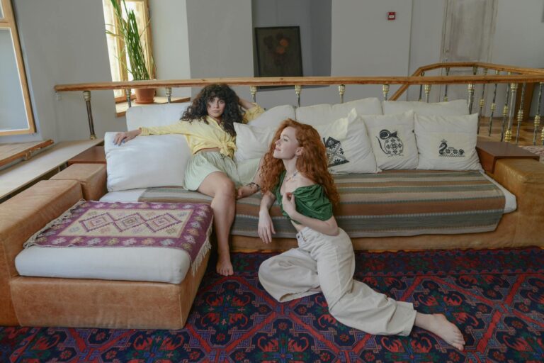 Two women relaxing on a stylish sofa in a cozy living room, exuding comfort and friendship.