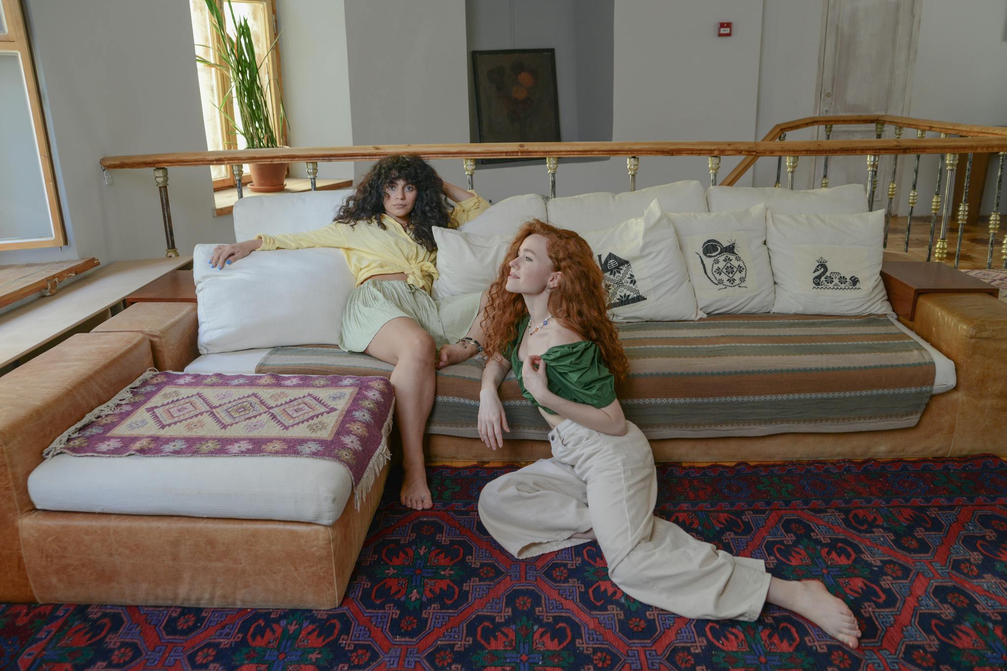 Two women relaxing on a stylish sofa in a cozy living room, exuding comfort and friendship.